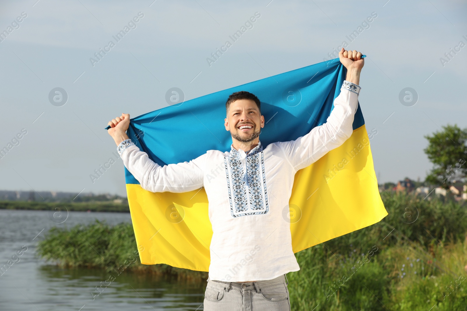 Man in vyshyvanka with flag of Ukraine outdoors Photo of Man in vyshyvanka with flag of Ukraine outdoors