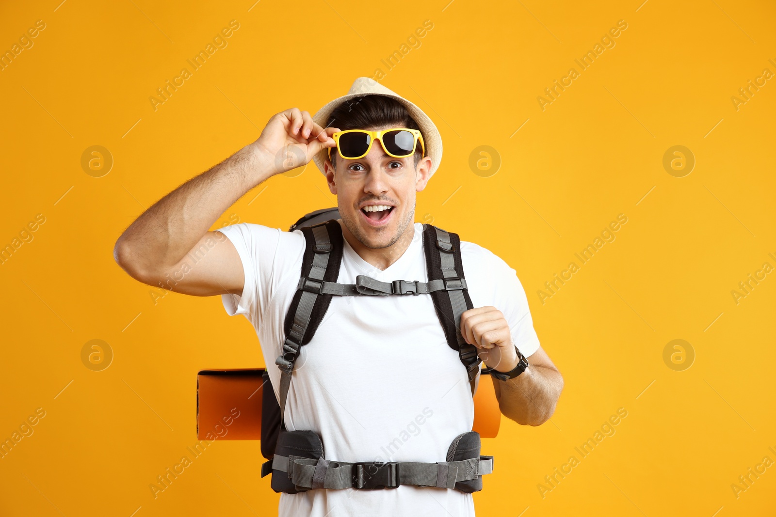 Emotional male tourist with travel backpack on yellow background Photo of Emotional male tourist with travel backpack on yellow background