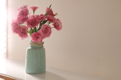 Bouquet of beautiful Eustoma flowers on table near light wall. Space for text Photo of Bouquet of beautiful Eustoma flowers on table near light wall. Space for text