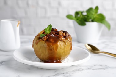 Delicious baked apple with nuts, caramel and mint served on white marble table Photo of Delicious baked apple with nuts, caramel and mint served on white marble table