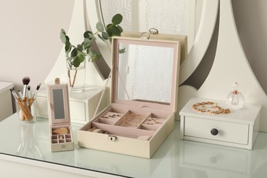 Jewelry boxes with stylish golden bijouterie on white dressing table Photo of Jewelry boxes with stylish golden bijouterie on white dressing table
