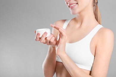 Young woman with jar of body cream on color background Photo of Young woman with jar of body cream on color background