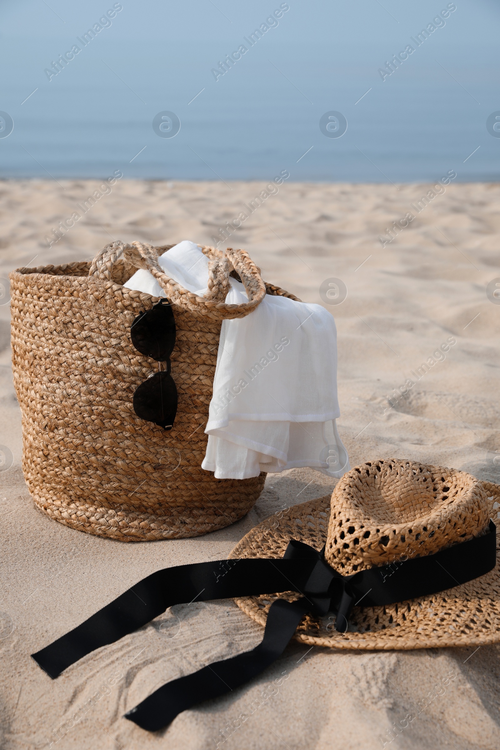 Beach bag, towel, sunglasses and hat on sandy seashore Photo of Beach bag, towel, sunglasses and hat on sandy seashore