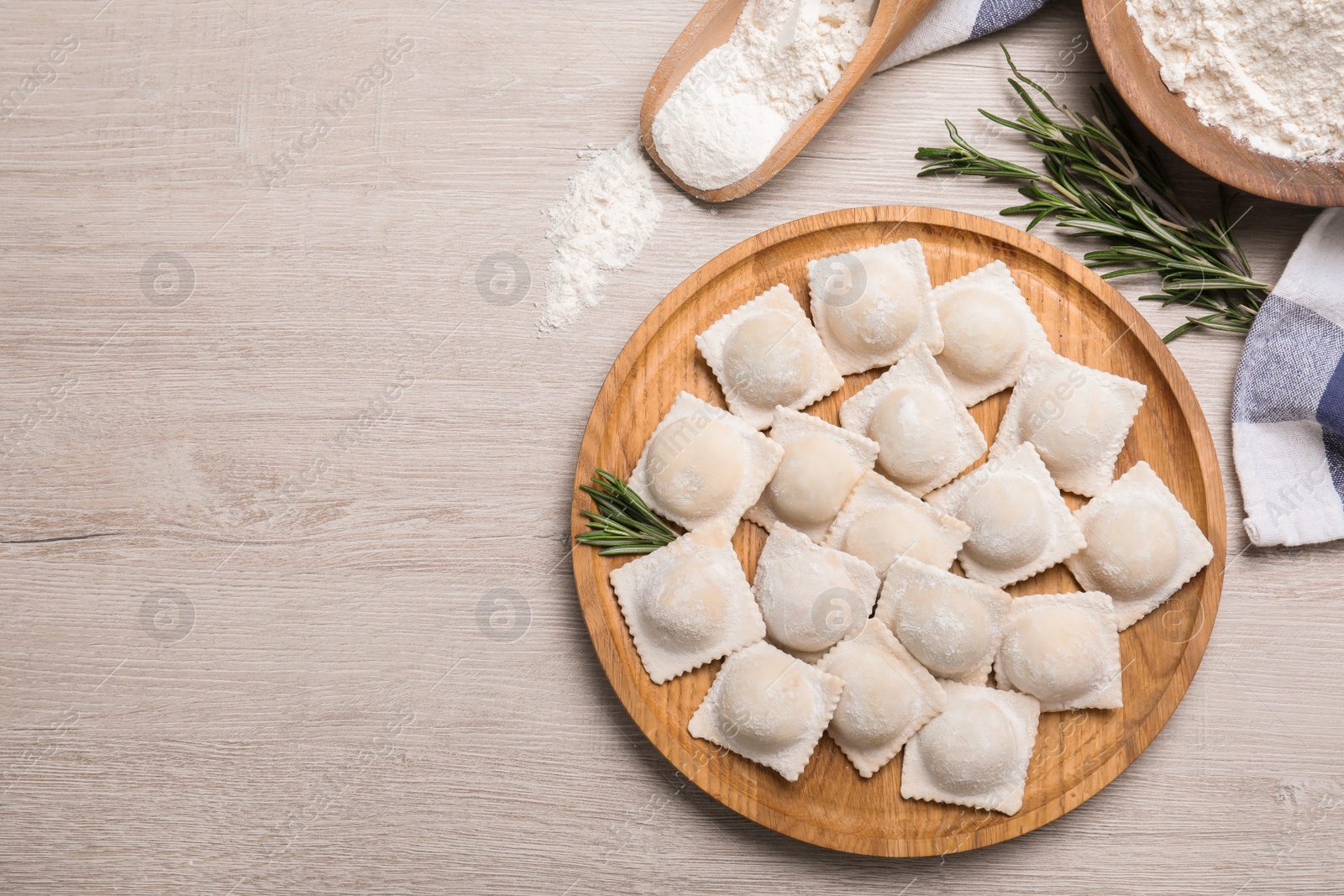 Uncooked ravioli and rosemary on white wooden table, flat lay. Space for text Photo of Uncooked ravioli and rosemary on white wooden table, flat lay. Space for text