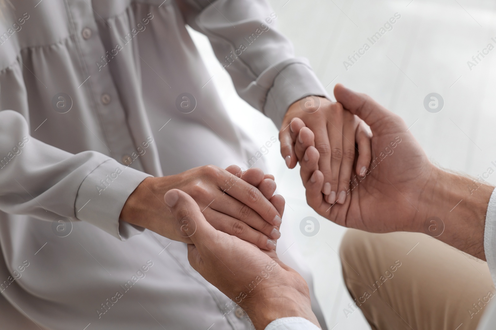 Photo of Religious people holding hands and praying together indoors, closeup
