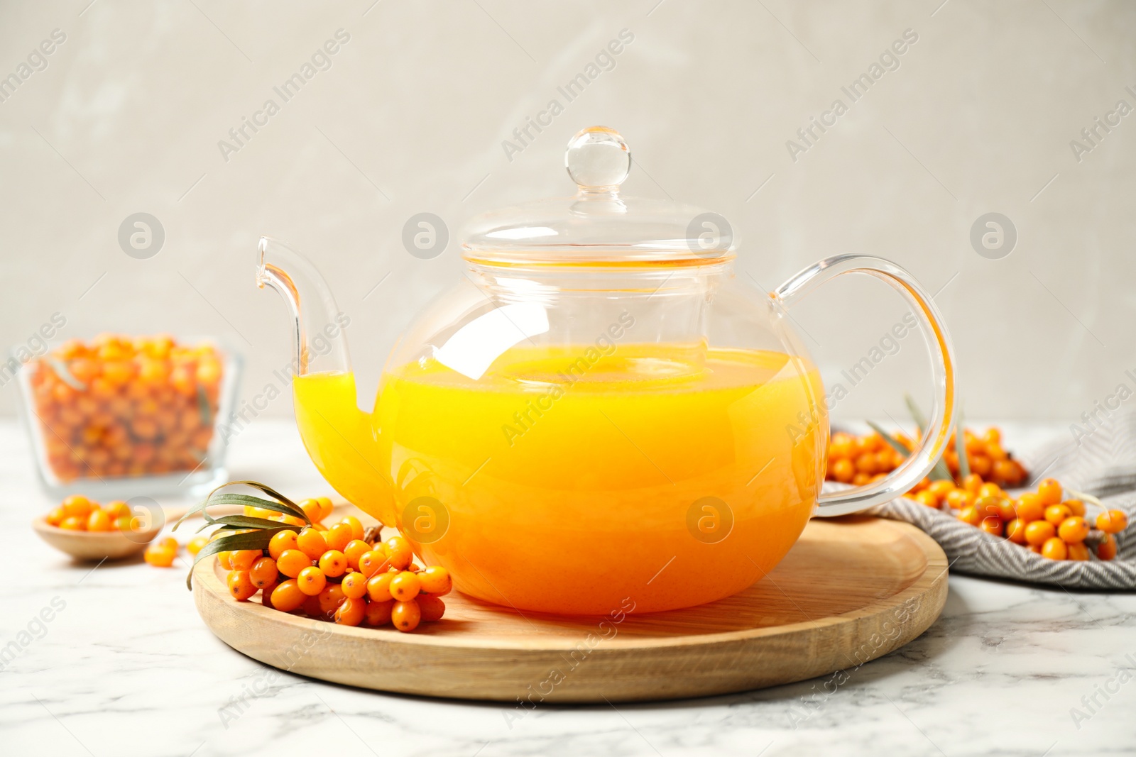 Delicious sea buckthorn tea and fresh berries on white marble table Photo of Delicious sea buckthorn tea and fresh berries on white marble table
