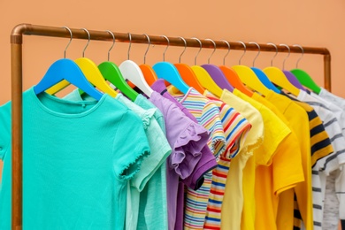 Photo of Rack with stylish children clothes on beige background, closeup
