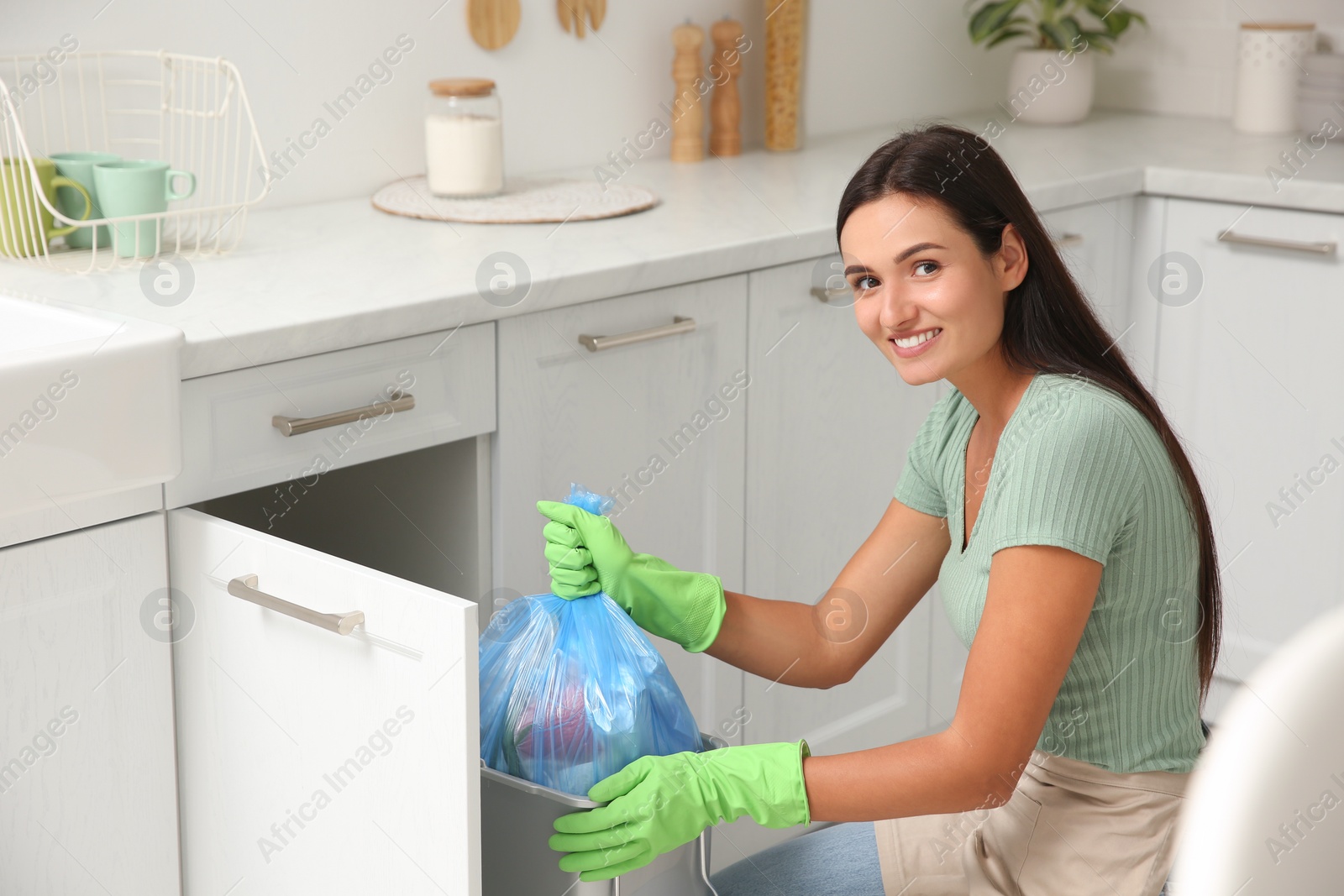 Woman taking garbage bag out of bin at home Photo of Woman taking garbage bag out of bin at home