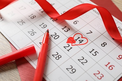 Calendar with marked Valentine's Day, red ribbon and marker on wooden table, closeup Photo of Calendar with marked Valentine's Day, red ribbon and marker on wooden table, closeup