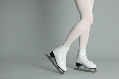 Woman in elegant white ice skates on grey background, closeup of legs. Space for text Photo of Woman in elegant white ice skates on grey background, closeup of legs. Space for text