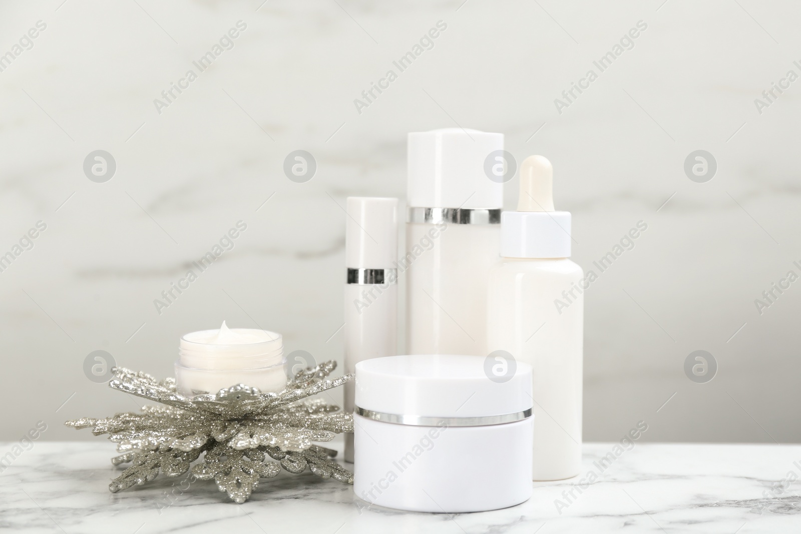 Beautiful composition with cosmetic products on white marble table. Winter care Photo of Beautiful composition with cosmetic products on white marble table. Winter care
