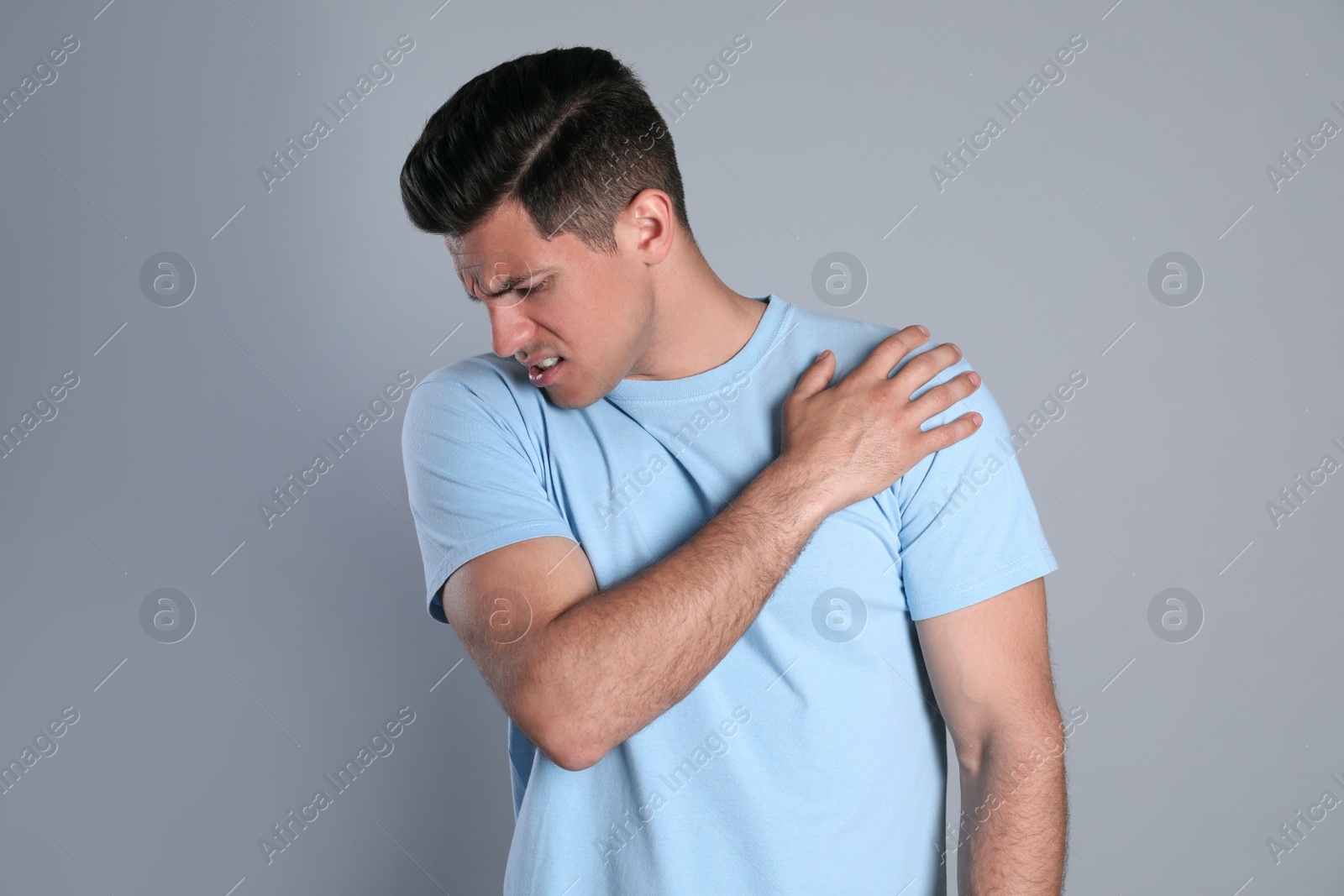 Man suffering from shoulder pain on grey background Photo of Man suffering from shoulder pain on grey background