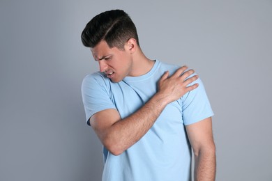 Man suffering from shoulder pain on grey background Photo of Man suffering from shoulder pain on grey background