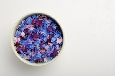 Beautiful colorful cornflowers petals in bowl on white table, top view. Space for text Photo of Beautiful colorful cornflowers petals in bowl on white table, top view. Space for text