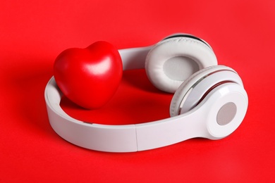 Modern headphones and heart on red background. Listening love music songs Photo of Modern headphones and heart on red background. Listening love music songs