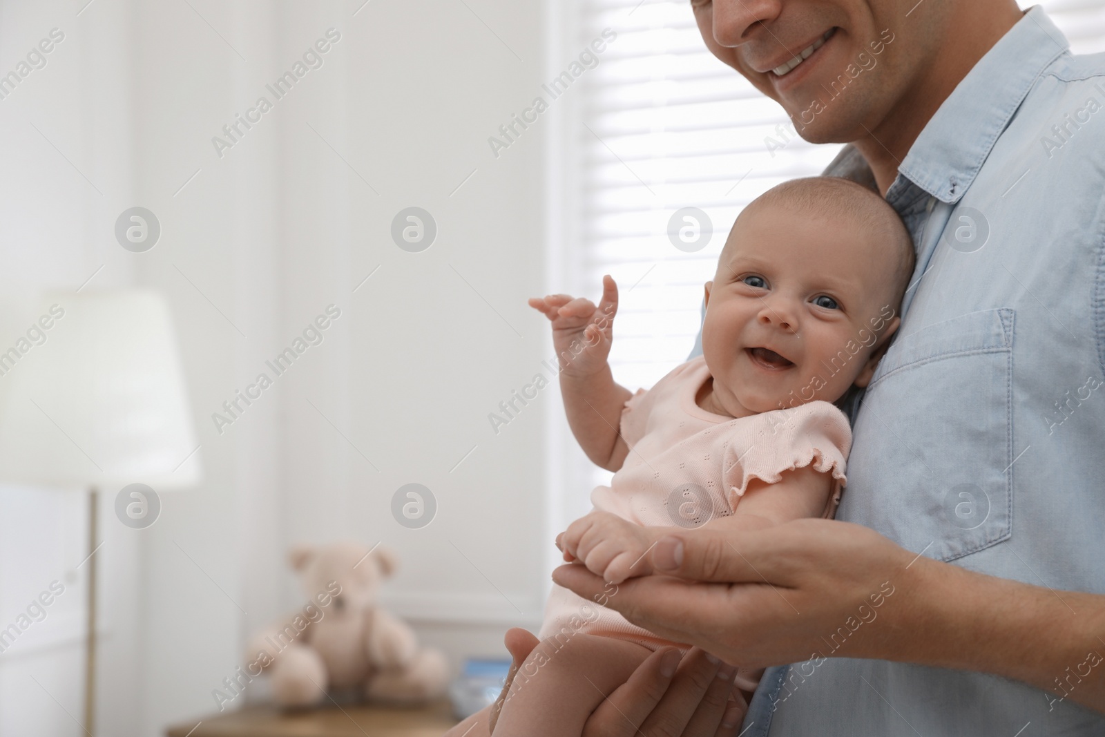 Happy father holding his cute little baby at home, closeup. Space for text Photo of Happy father holding his cute little baby at home, closeup. Space for text