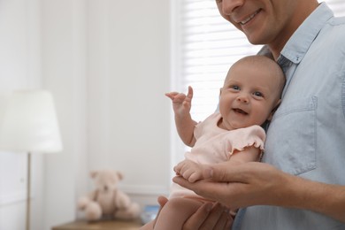 Happy father holding his cute little baby at home, closeup. Space for text Photo of Happy father holding his cute little baby at home, closeup. Space for text