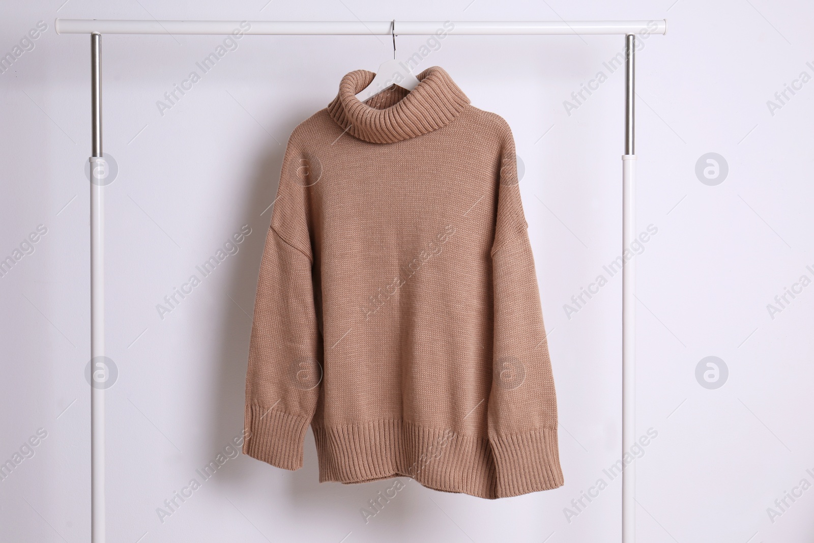 Warm sweater hanging on rack against white background Photo of Warm sweater hanging on rack against white background