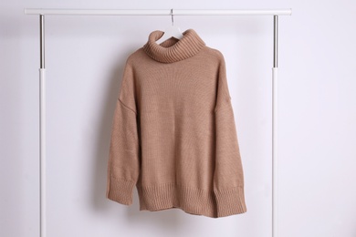 Warm sweater hanging on rack against white background Photo of Warm sweater hanging on rack against white background