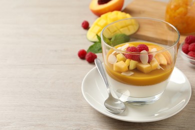 Delicious panna cotta with mango coulis, fresh fruit pieces and almond flakes on light wooden table. Space for text Photo of Delicious panna cotta with mango coulis, fresh fruit pieces and almond flakes on light wooden table. Space for text