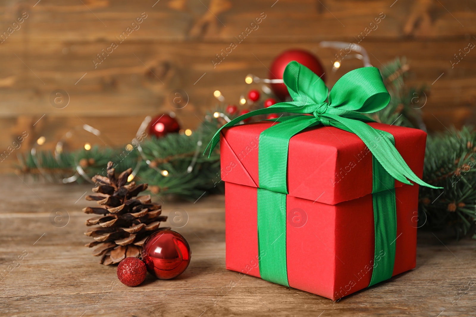 Red gift box with green bow and Christmas decor on wooden table Photo of Red gift box with green bow and Christmas decor on wooden table