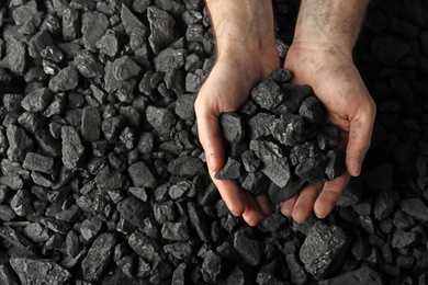 Man holding coal in hands over pile, top view. Space for text Photo of Man holding coal in hands over pile, top view. Space for text