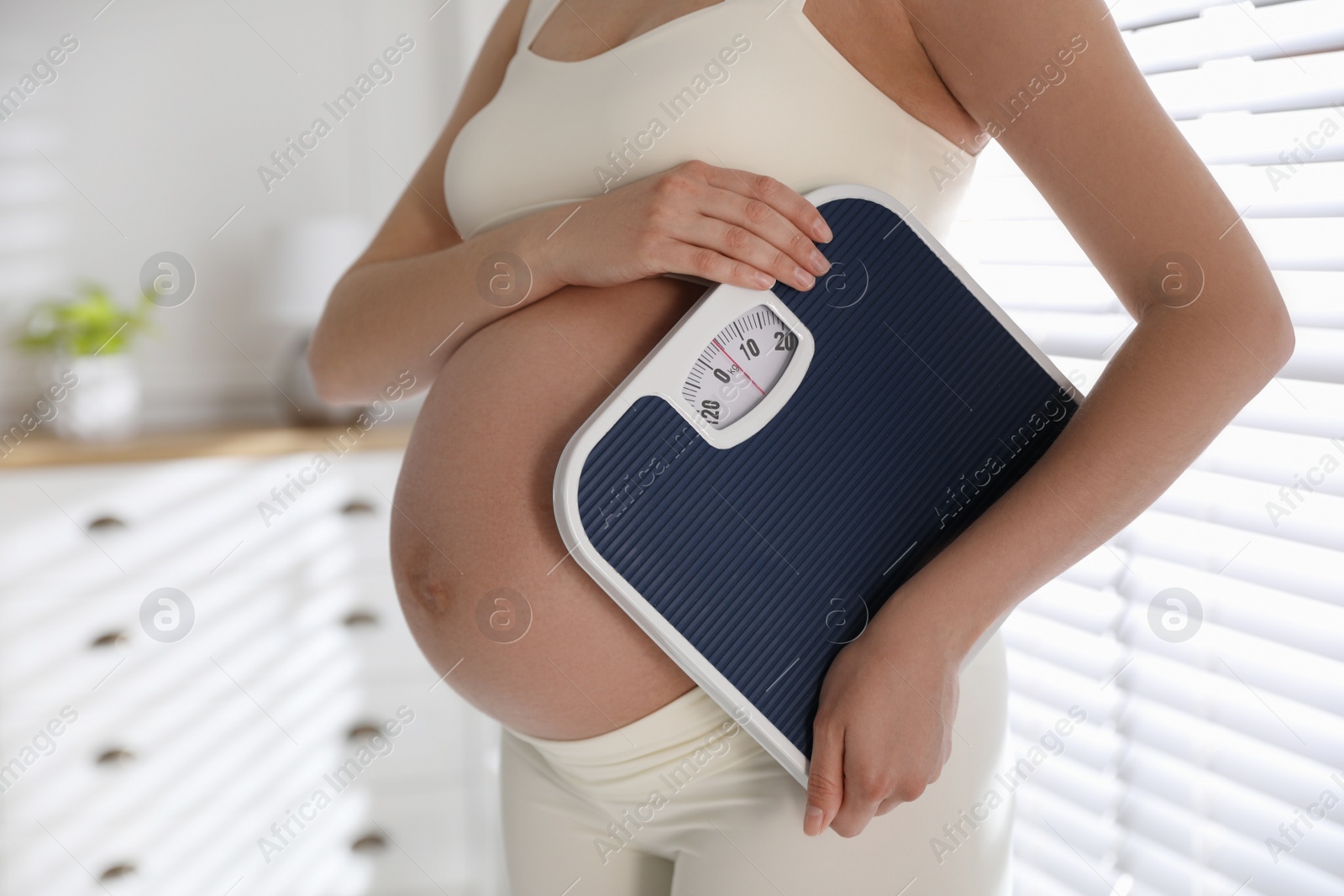 Young pregnant woman with scales at home, closeup Photo of Young pregnant woman with scales at home, closeup