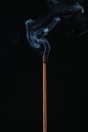 Incense stick smoldering on black background, closeup Photo of Incense stick smoldering on black background, closeup