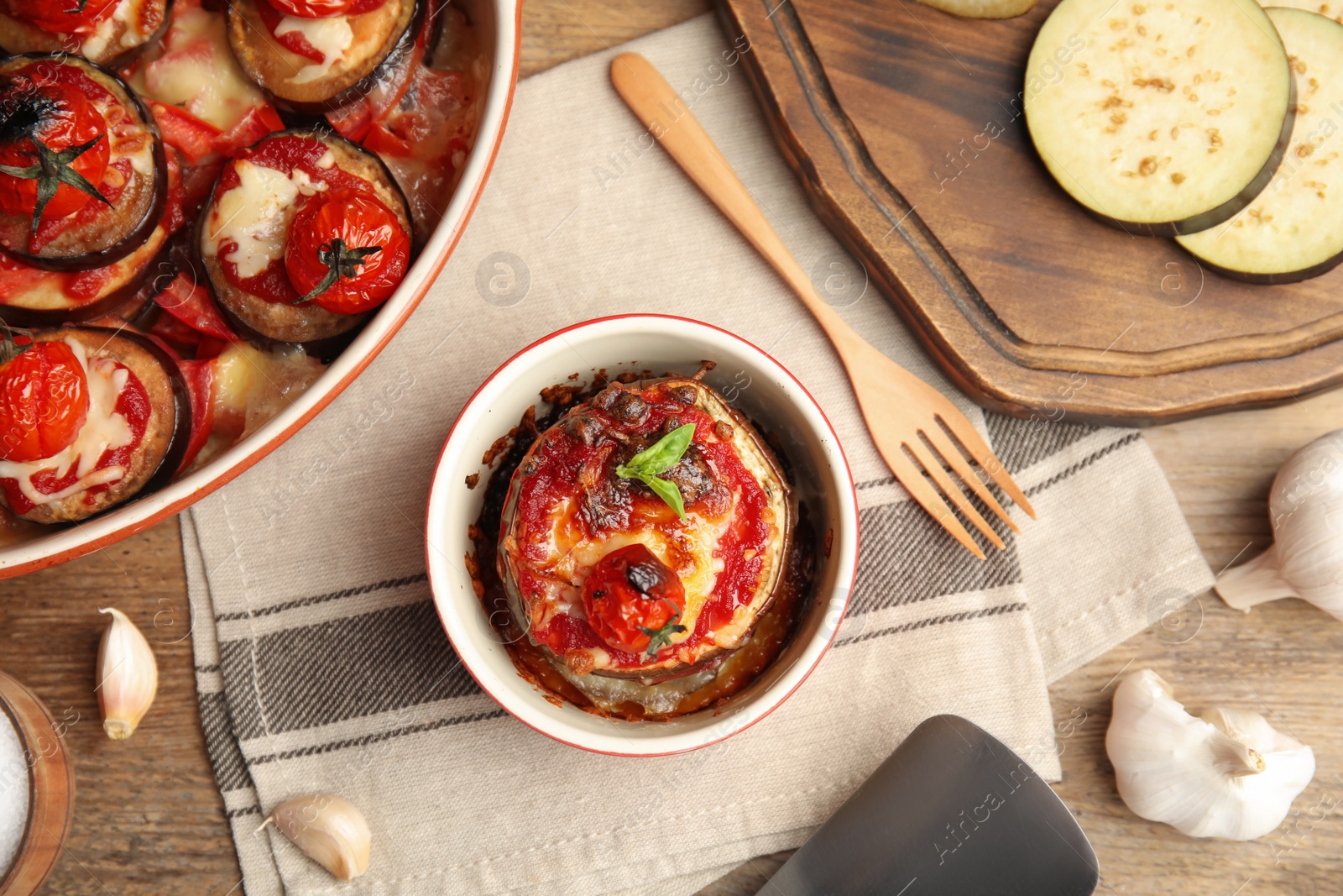 Baked eggplant with tomatoes, cheese and basil served on wooden table, flat lay Photo of Baked eggplant with tomatoes, cheese and basil served on wooden table, flat lay
