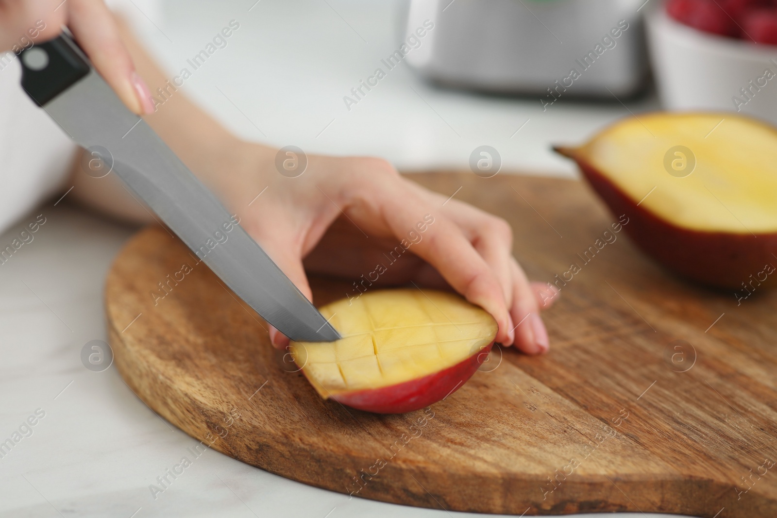 Woman preparing mango for tasty smoothie at white marble table, closeup Photo of Woman preparing mango for tasty smoothie at white marble table, closeup