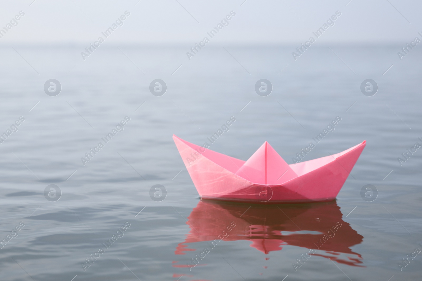 Pink paper boat on water surface, space for text Photo of Pink paper boat on water surface, space for text