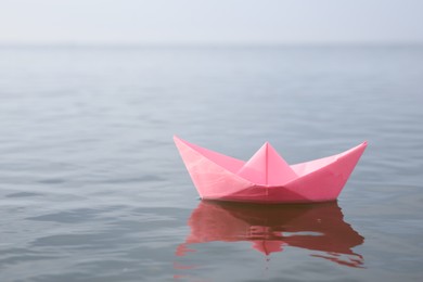 Pink paper boat on water surface, space for text Photo of Pink paper boat on water surface, space for text