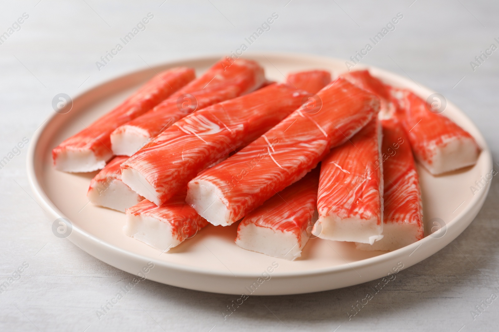 Plate of fresh crab sticks on white table, closeup Photo of Plate of fresh crab sticks on white table, closeup