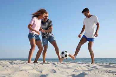 Group of friends playing football on beach Photo of Group of friends playing football on beach