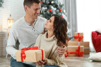 Happy couple with Christmas gift at home Image of Happy couple with Christmas gift at home