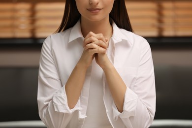 Religious woman with clasped hands praying indoors, closeup Photo of Religious woman with clasped hands praying indoors, closeup