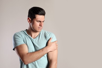 Man suffering from shoulder pain on beige background. Space for text Photo of Man suffering from shoulder pain on beige background. Space for text