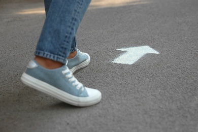 Person standing near arrow on asphalt, closeup Photo of Person standing near arrow on asphalt, closeup