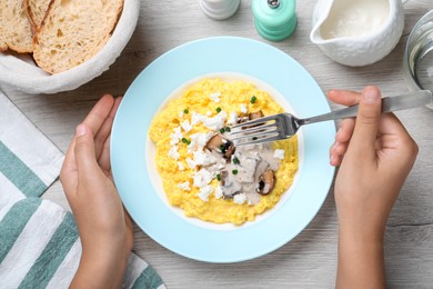 Woman eating banosh with brynza and mushrooms at light wooden table, top view. Traditional Ukrainian dish Photo of Woman eating banosh with brynza and mushrooms at light wooden table, top view. Traditional Ukrainian dish