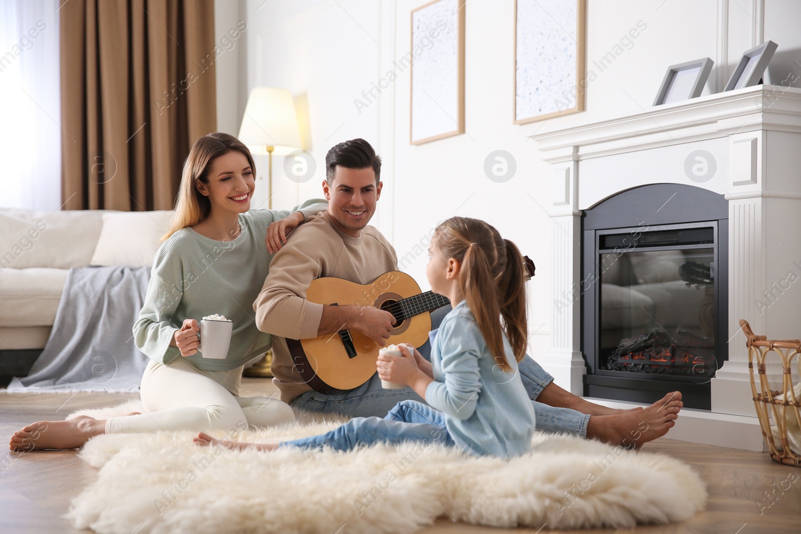 Happy family spending time together near fireplace at home Photo of Happy family spending time together near fireplace at home
