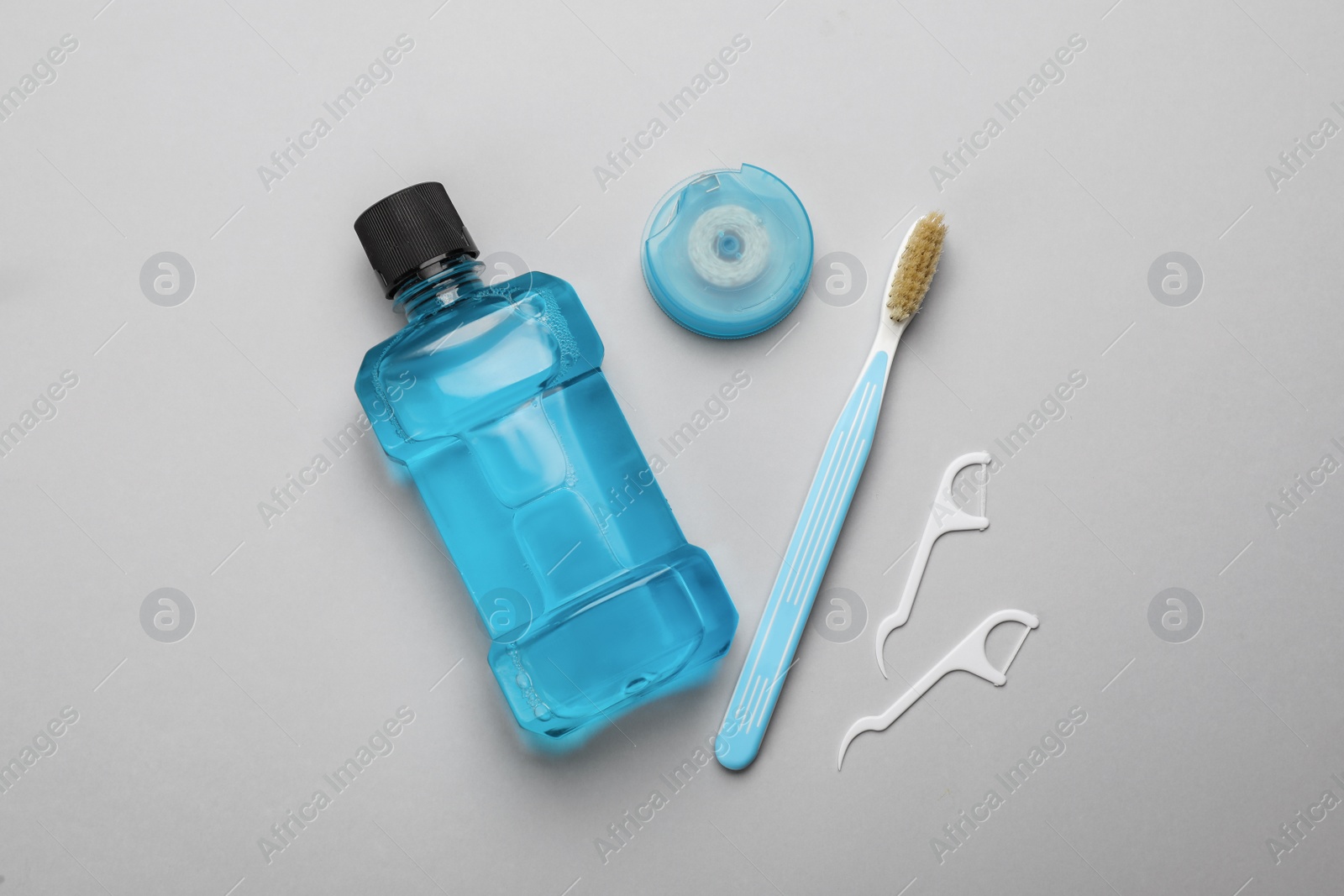 Mouthwash, toothbrush and dental floss on light grey background, flat lay Photo of Mouthwash, toothbrush and dental floss on light grey background, flat lay