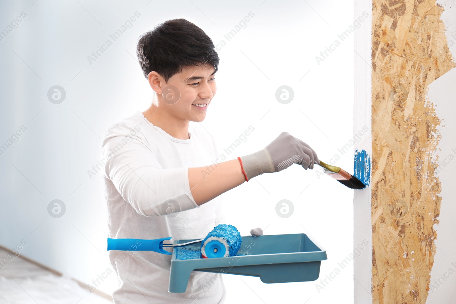 Male decorator painting wall with brush indoors Photo of Male decorator painting wall with brush indoors
