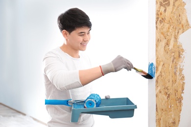 Male decorator painting wall with brush indoors Photo of Male decorator painting wall with brush indoors