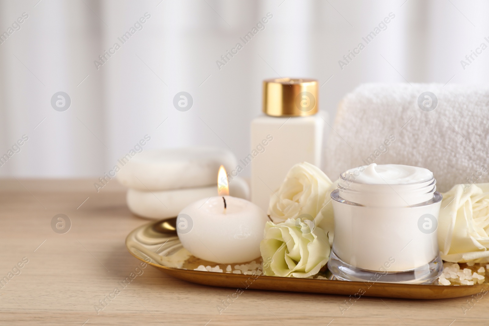 Spa composition with skin care products, flowers and candle on wooden table. Space for text Photo of Spa composition with skin care products, flowers and candle on wooden table. Space for text
