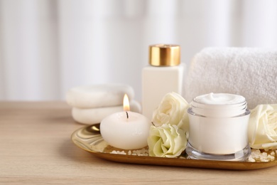 Spa composition with skin care products, flowers and candle on wooden table. Space for text Photo of Spa composition with skin care products, flowers and candle on wooden table. Space for text