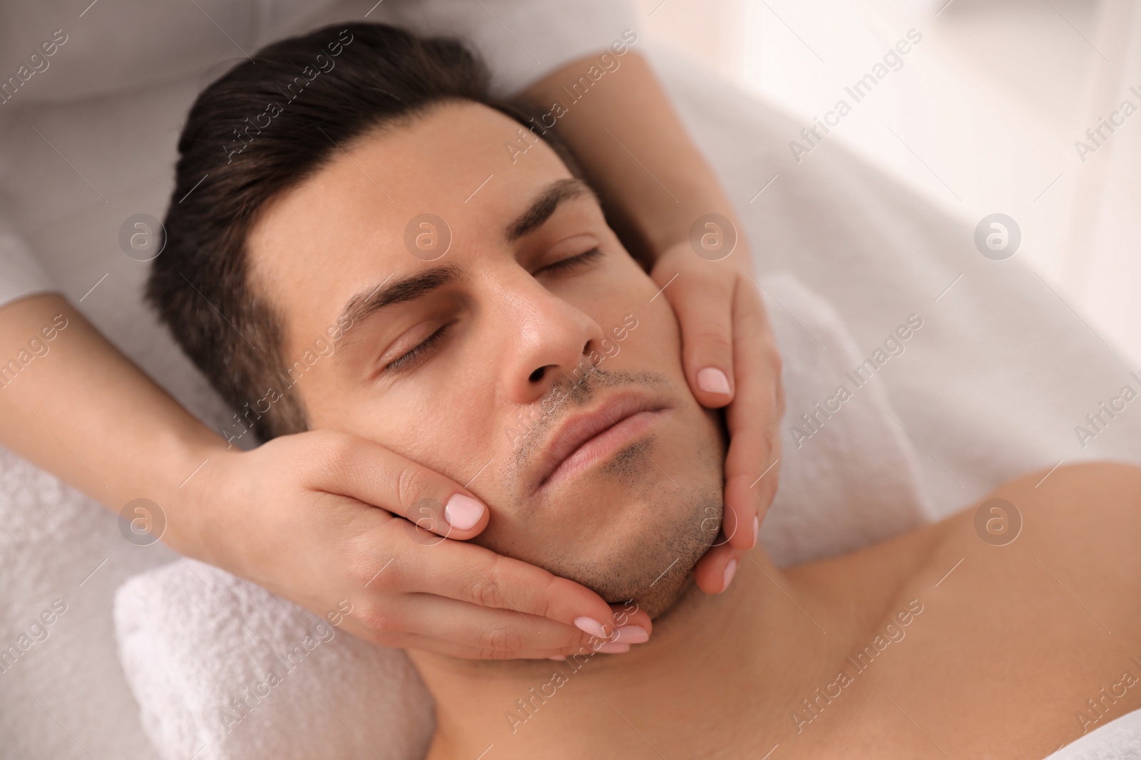 Man receiving facial massage in beauty salon, above view Photo of Man receiving facial massage in beauty salon, above view