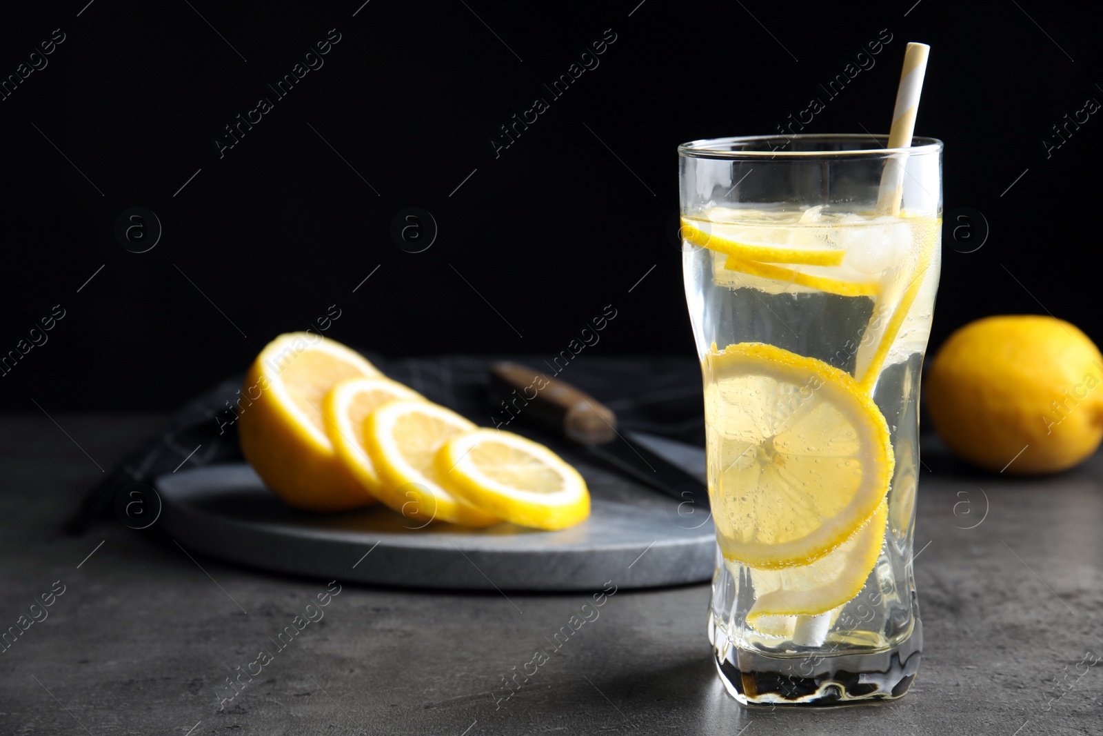 Soda water with lemon slices and ice cubes on grey table. Space for text Photo of Soda water with lemon slices and ice cubes on grey table. Space for text