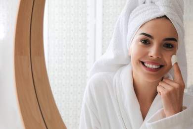 Woman using silkworm cocoon in skin care routine near mirror at home. Space for text Photo of Woman using silkworm cocoon in skin care routine near mirror at home. Space for text