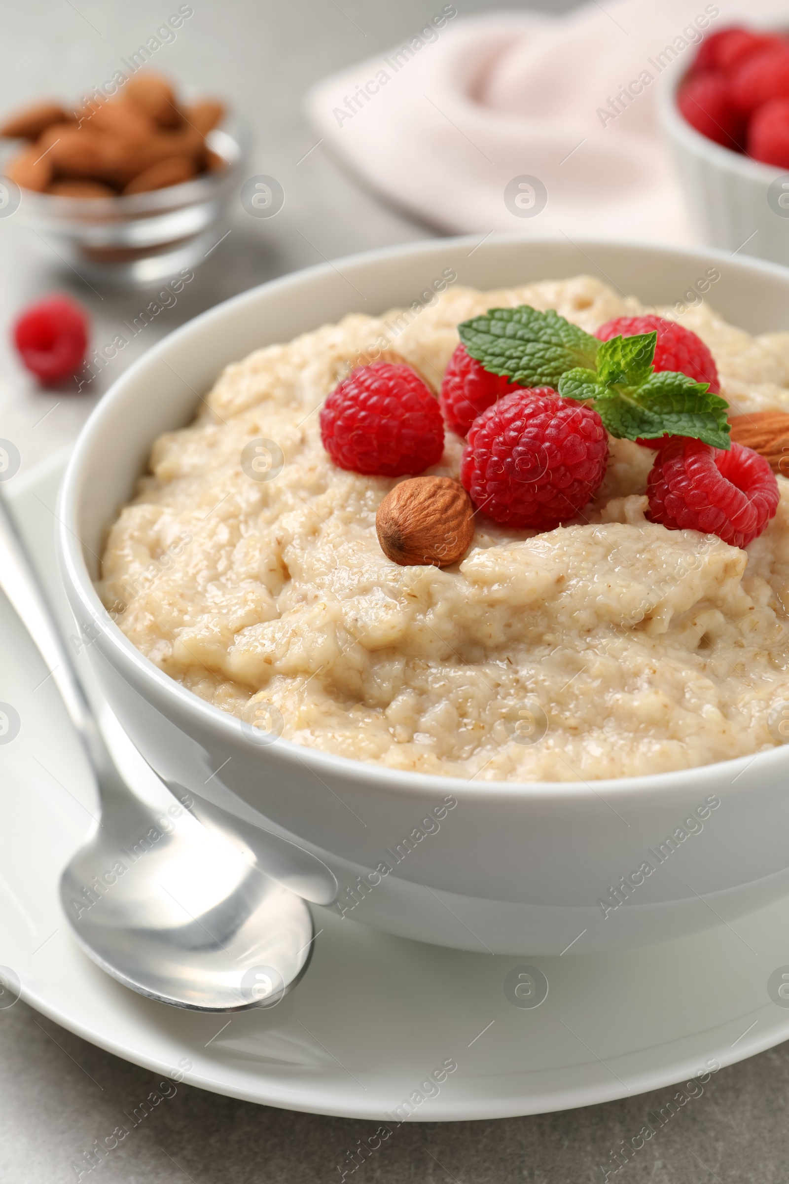 Tasty oatmeal porridge with raspberries and almond nuts served on table, closeup Photo of Tasty oatmeal porridge with raspberries and almond nuts served on table, closeup