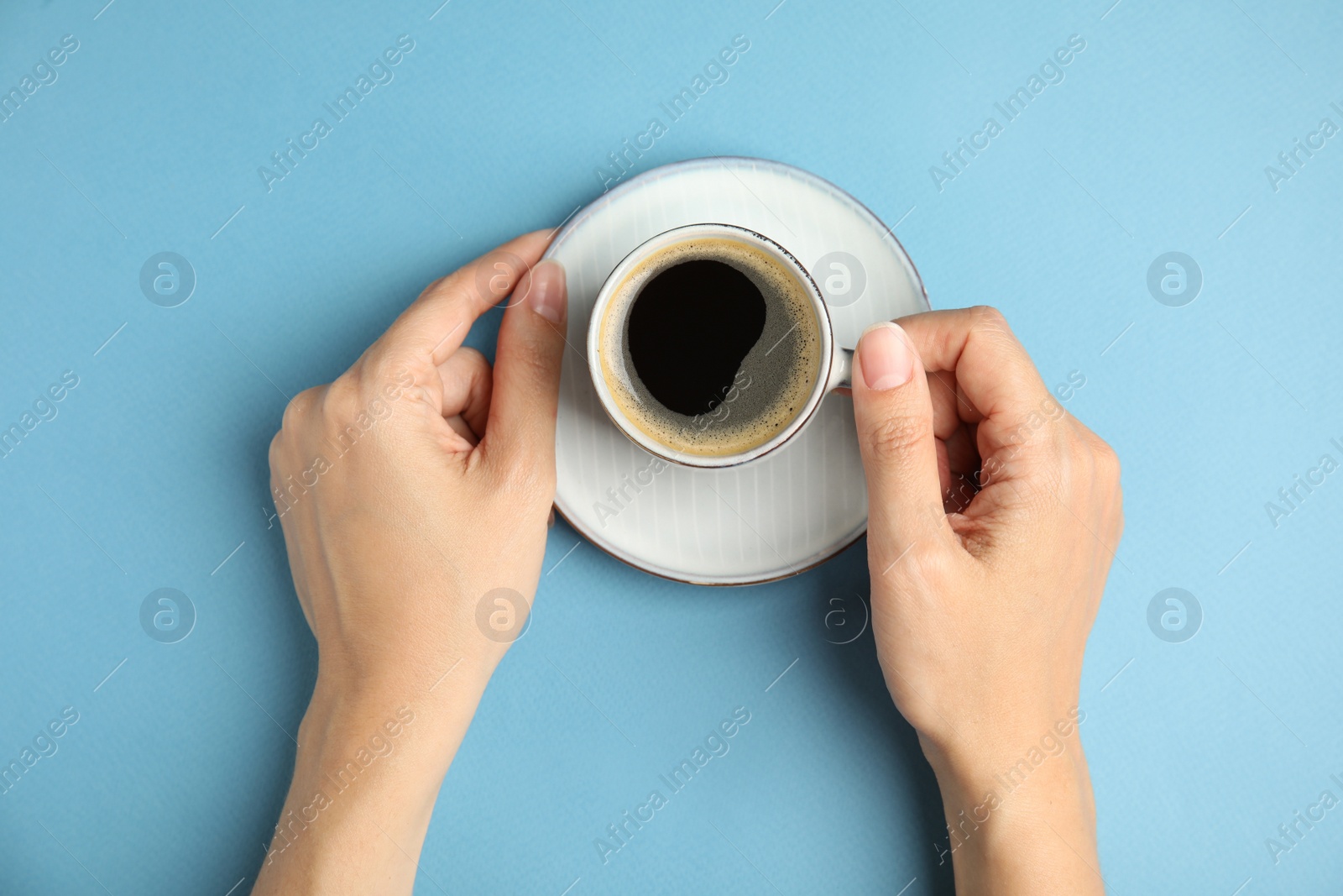 Woman with cup of hot aromatic espresso on light blue background, top view Photo of Woman with cup of hot aromatic espresso on light blue background, top view